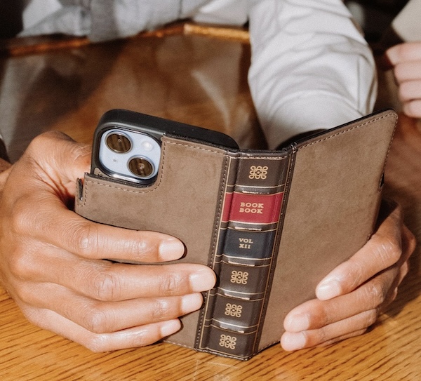 A man holding the BookBook phone case that looks like a book.