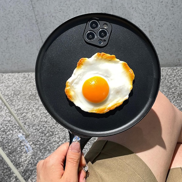 A picture of a phone case that looks like a frying pan that's frying an egg.