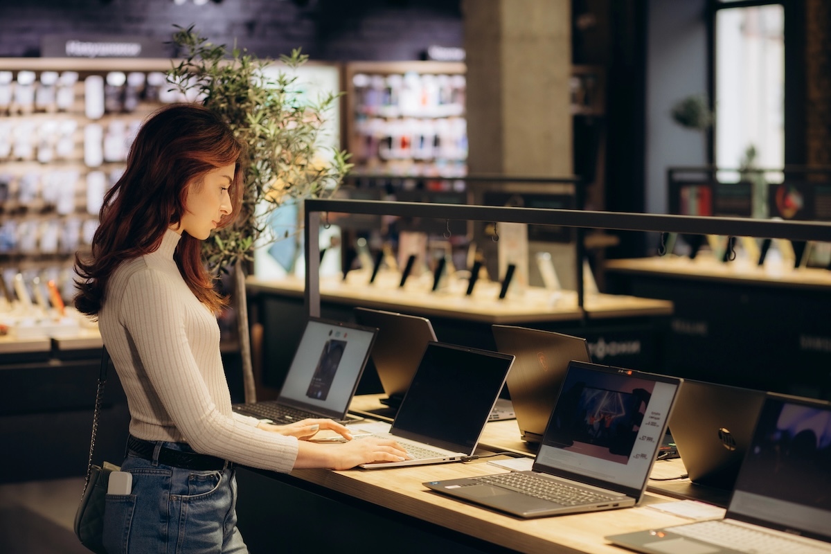 A photo of a woman trying out laptops at a store.